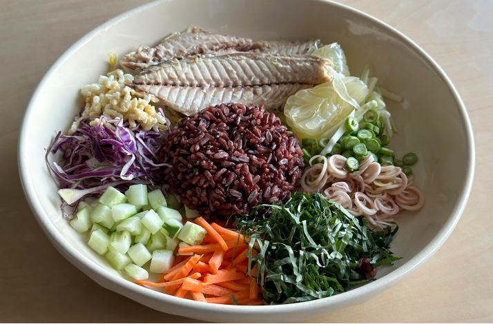 Colorful Thai rice salad bowl with fish and fresh vegetables.