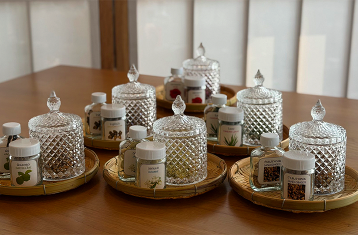 Trays of traditional Thai herbs and crystal jars arranged for a wellness workshop.
