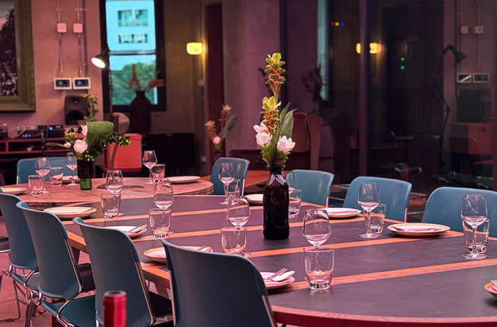  A dining table set with plates, glasses, and floral arrangements in a modern space.