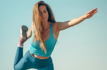  Person balancing in a standing yoga pose outdoors against a clear sky.