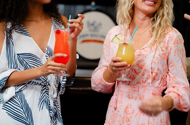 Guests holding colourful rum cocktails at the distillery.