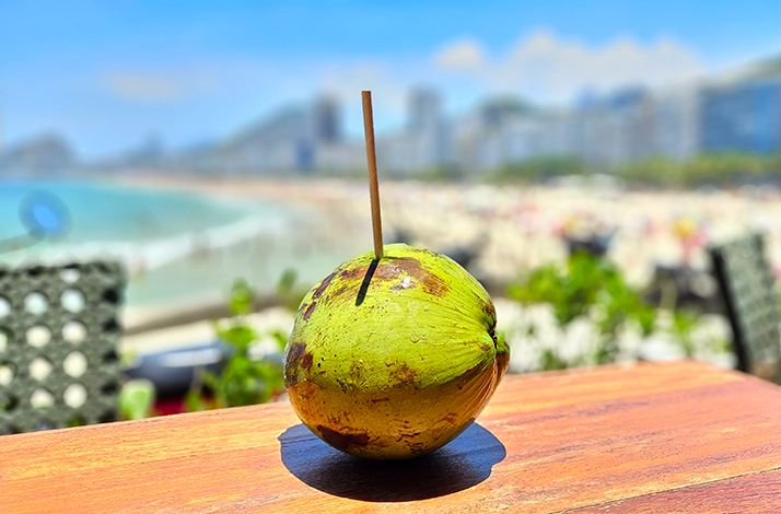 Fresh natural coconut water served at the beach in Rio de Janeiro, enjoyed as a refreshing moment after a capoeira session.