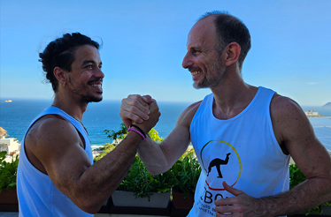 A symbolic greeting between capoeira participants overlooking the ocean in Rio de Janeiro, reflecting connection, respect, and cultural exchange.