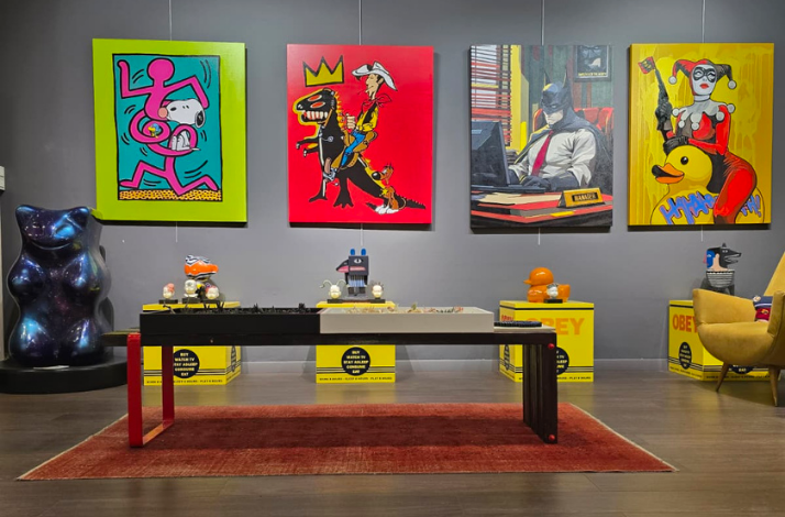 A contemporary gallery of Red Art İstanbul displays four pop-art paintings placed in front of a long black table
