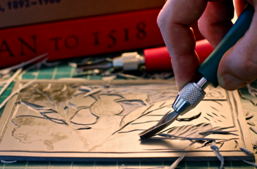 A person using a knife to cut a piece of paper on a flat surface.