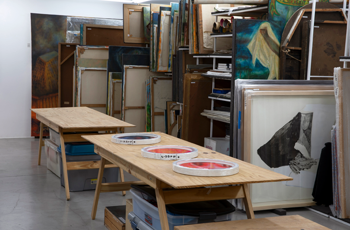 Worktables surrounded by stored artworks, revealing the behind-the-scenes