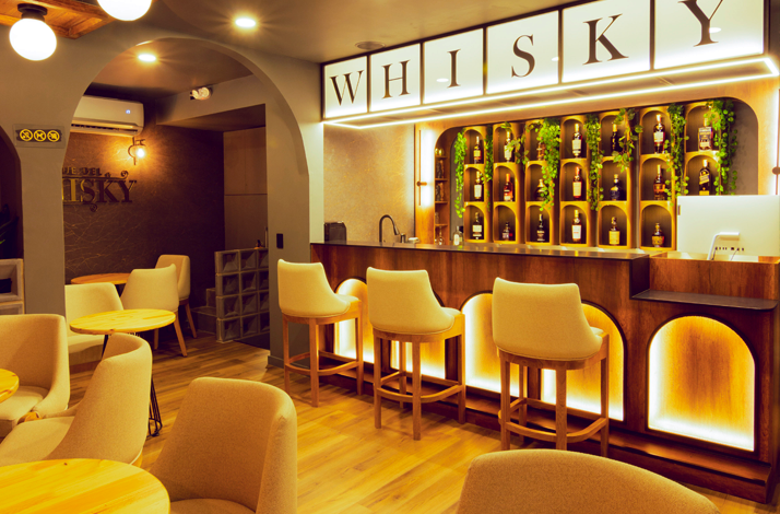 illuminated with shelves of whiskies from various regions around the world, with chairs set along the counter