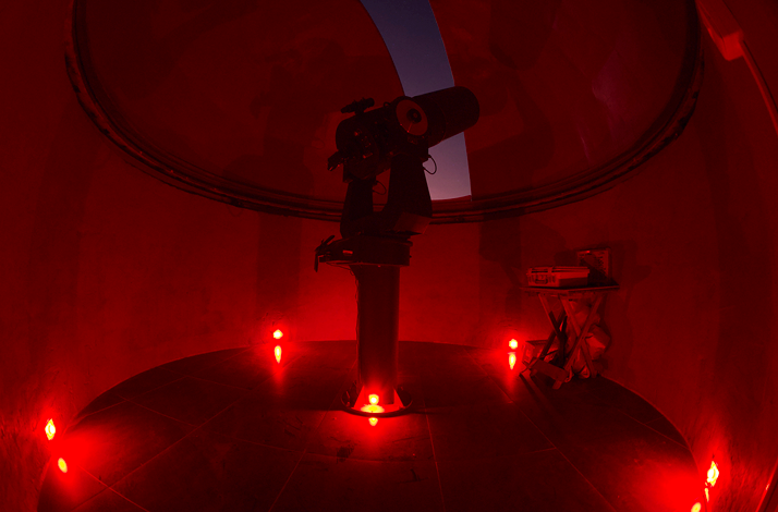 Telescope illuminated with red lights inside a dome during the Andean Skies experience