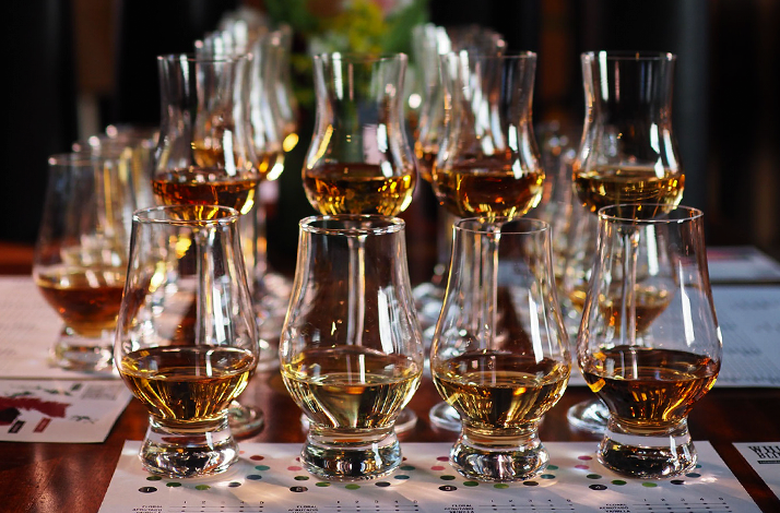 Rows of Glencairn glasses filled with golden whisky pours prepared for a blind tasting experience at Whisky Blinders – Gente de Mezcal.