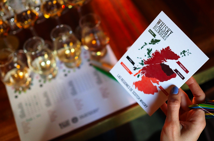 Hand holding a Whisky Blinders tasting card highlighting Scotch single-cask drams imported from Scotland, part of the guided blind tasting.