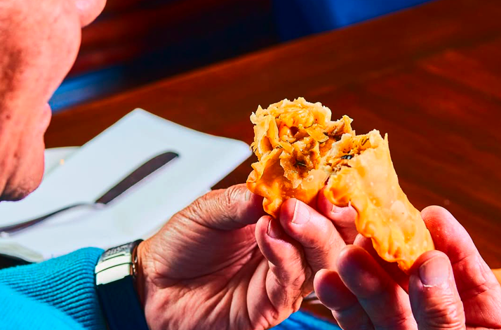 Close-up of a seafood empanada opened to reveal its warm, savory filling.