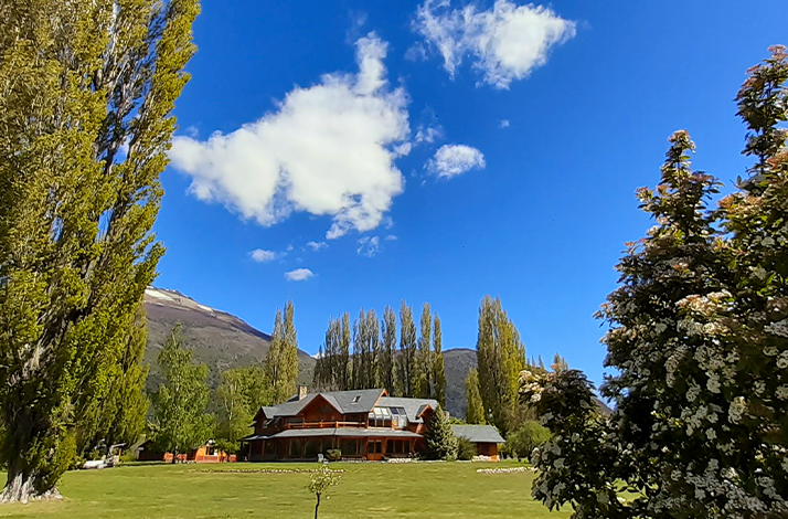Rest lodge surrounded by trees and mountains under a clear sky