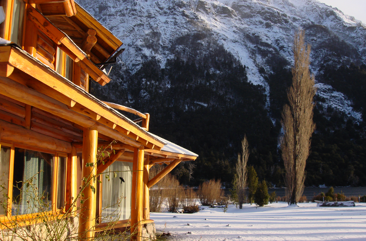 Wooden eco‑lodge framed by snow‑dusted mountains, reflecting stillness and connection with nature.
