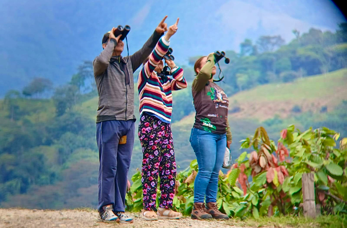 Three people pointing at a abird they watched