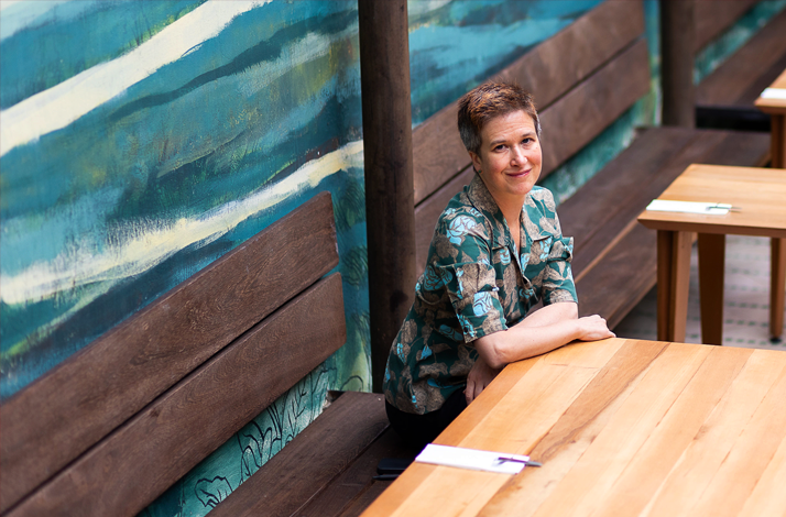 Meghan Flanigan seated at a wooden table inside Prudencia Restaurant