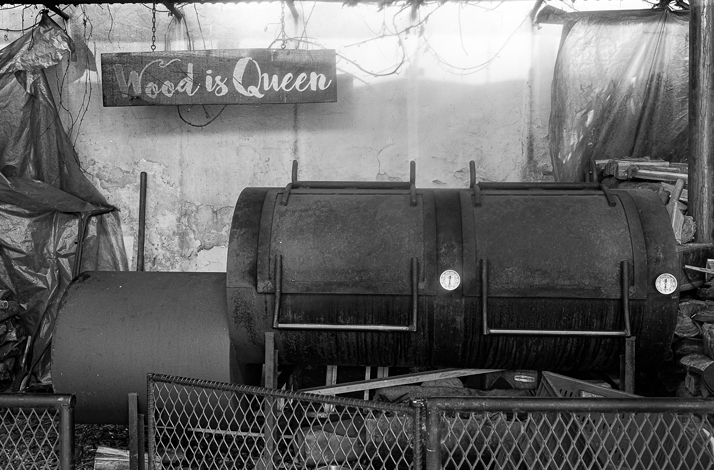 Wood-fired smoker in the foreground, showcasing the fire-based cooking techniques