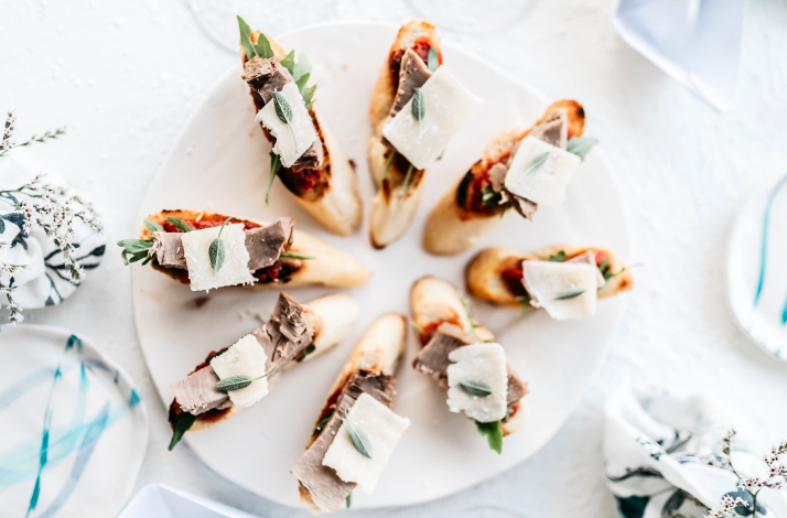 Plate of gourmet crostini topped with cheese, herbs, and savory spreads.