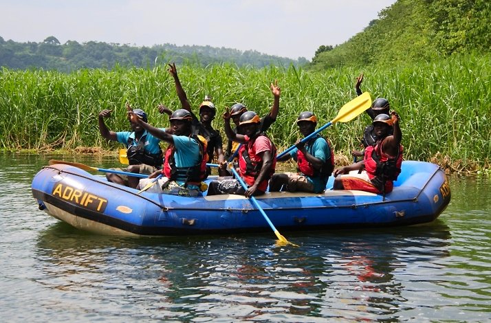 Excited group of rafters in calm waters surrounded by lush greenery during a Nile River adventure.