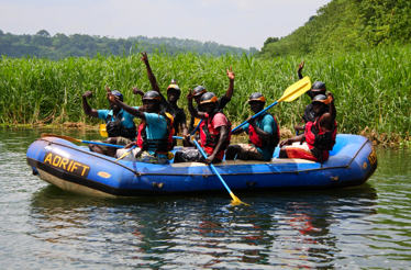Excited group of rafters in calm waters surrounded by lush greenery during a Nile River adventure.