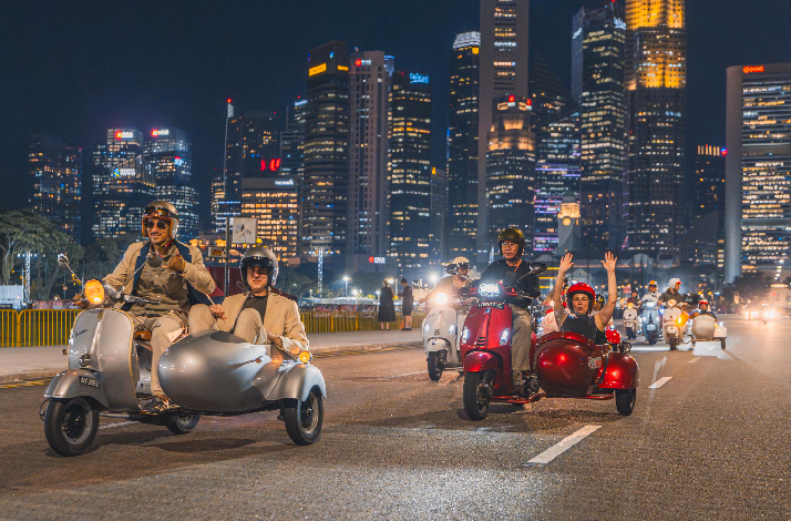 People riding the streets of Singapore in vintage Vespa sidecars