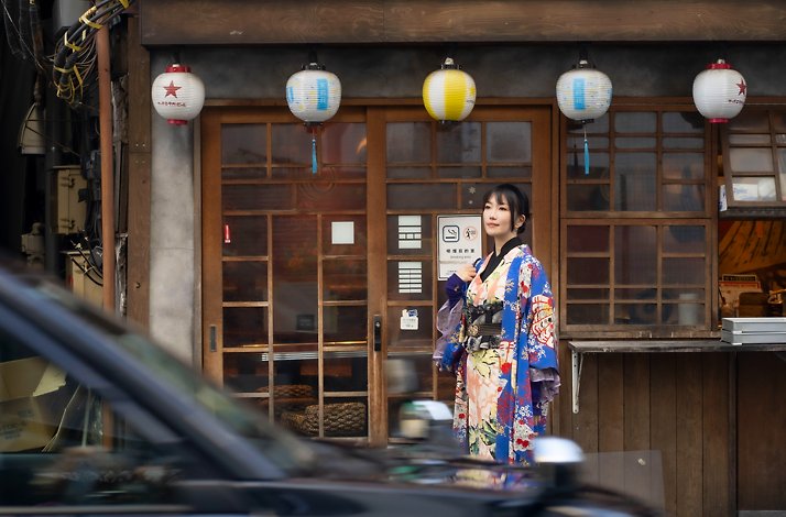 Sankak in a colorful kimono standing in front of the Kimono Hazuki shop.