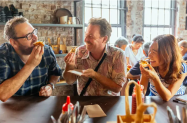 Three people enjoying casual dining together at a rustic restaurant table.