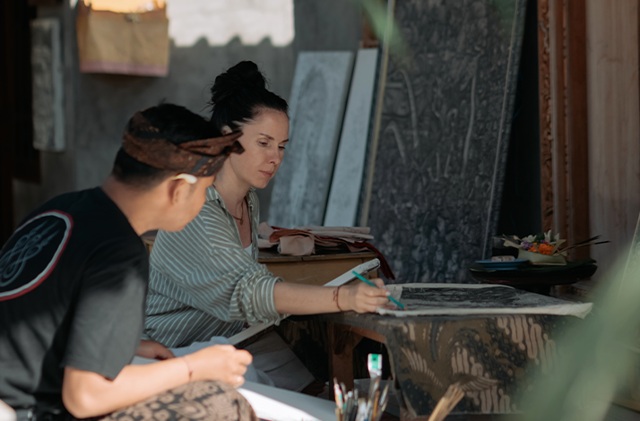 Balinese artist guiding a visitor in painting at a home in Batuan Village.