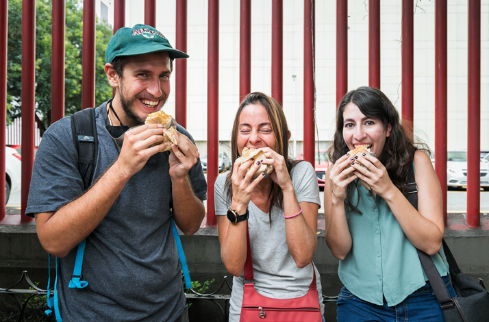 Three participants enjoying Mexico City street food during a guided tasting tour in the Cuauhtémoc neighborhood.