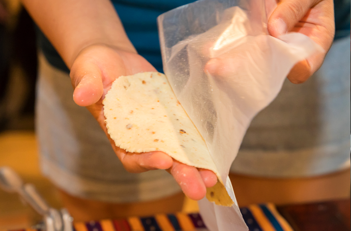 Hands shaping fresh masa into tortillas on a traditional comal.
