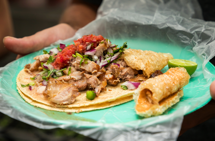 Freshly prepared Mexico City street food served at a sidewalk stand, featuring a filled tortilla and traditional accompaniments.