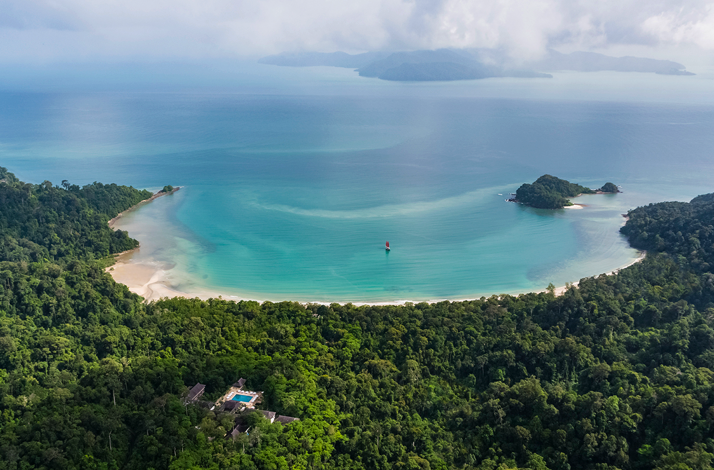 Aerial view of The Datai Langkawi resort nestled in a lush rainforest overlooking the turquoise waters of Datai Bay.
