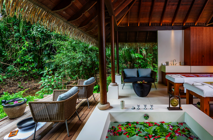 Luxury open-air spa villa at The Datai Langkawi featuring a floral bath and massage beds facing a lush rainforest.