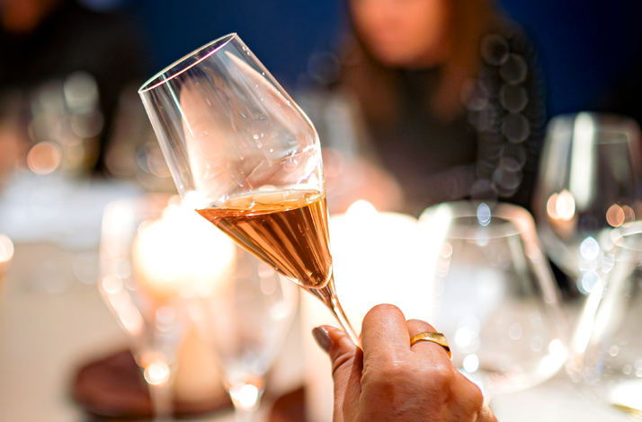 Wine glass held up to evaluate color and clarity during tasting.