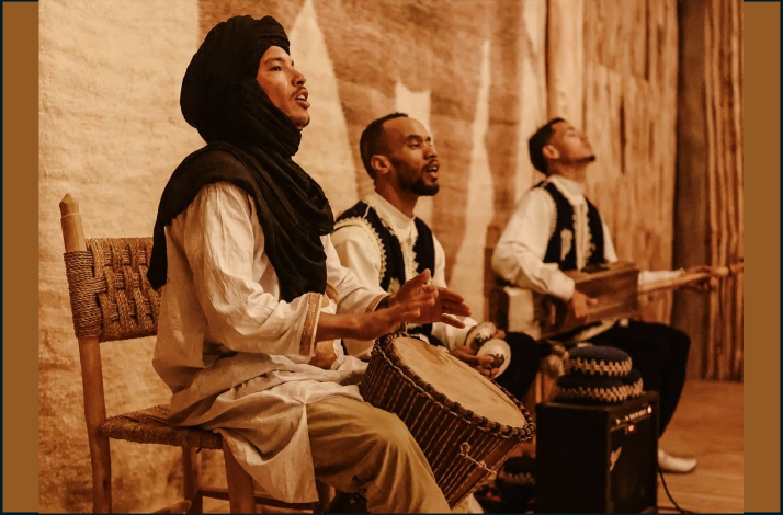 Three musicians in traditional Moroccan attire performing indoors.