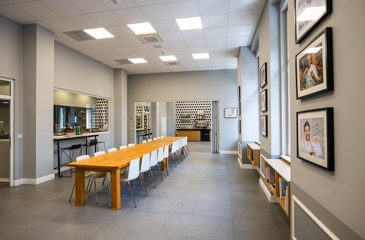 Bright classroom with a long wooden table, chairs, and pastry academy decor.