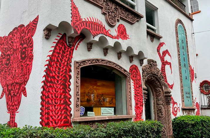 Exterior view of Galería Oscar Román featuring striking red contemporary murals on the façade.