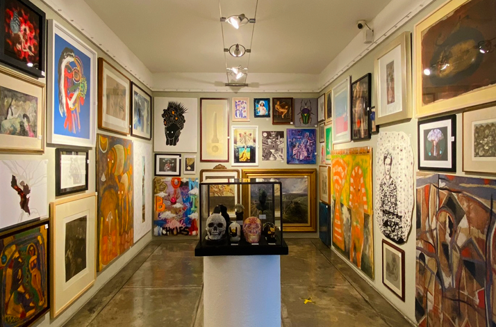 Room filled with various paintings and center decoration at Galería Oscar Román.
