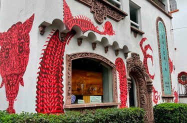 Exterior view of Galería Oscar Román featuring striking red contemporary murals on the façade.