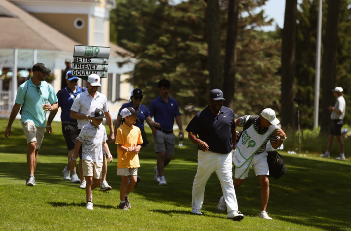 Guests walking alongside players at Drive Fore Kids celebrity golf tournament at Falmouth Country Club.