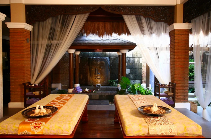 An outdoor massage pavilion features two spa beds and a large stone Buddha face statue at Tirta Spa in Boracay, Philippines.