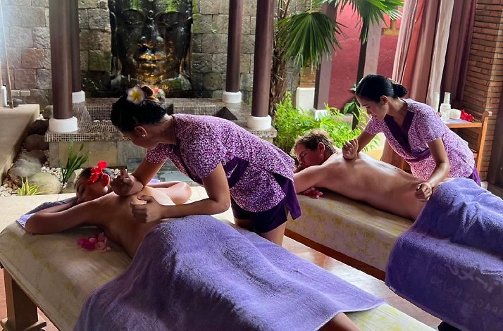 Two therapists perform couple massages near a stone Buddha fountain at Tirta Spa in Boracay, Philippines.