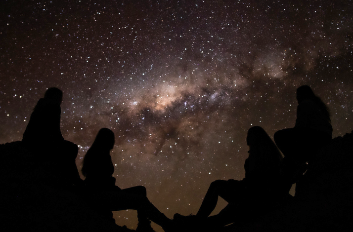 Four shadows of people with the universe and stars in the background at Atacama Desert.