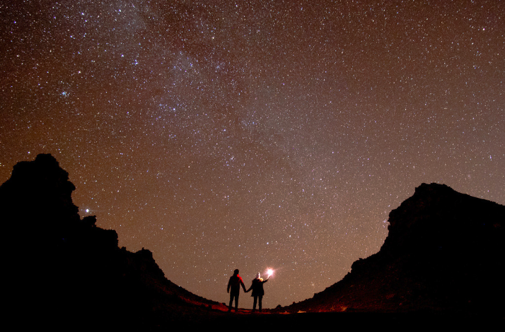 Two people with a lantern seeing the stars at Atacama Desert.