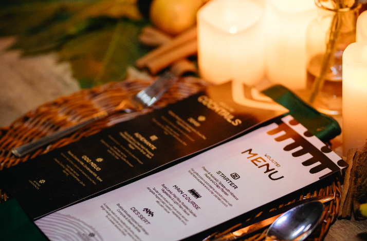 Close-up of the evening's menu displayed on a wicker placemat alongside candles and traditional decor.