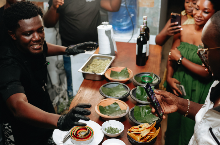 Chef Fiifi preparing dishes in the kitchen, surrounded by guests eager to learn about the culinary process.