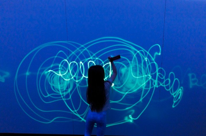Child drawing with light on an interactive wall at Dream Point.