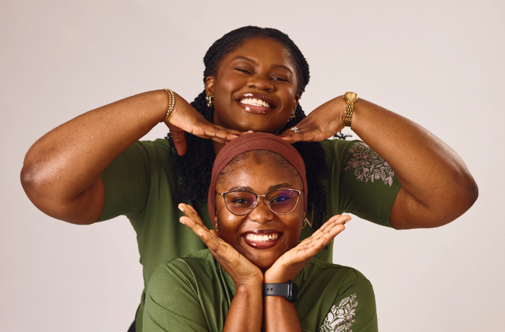 Two women in matching green tops smiling and posing playfully together at Nairobi Supper Club dining event.