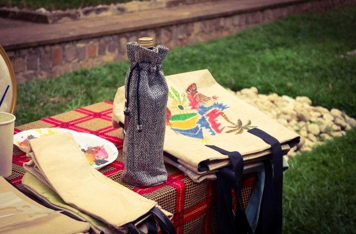 Handcrafted bags and a bottle displayed on a table outdoors.