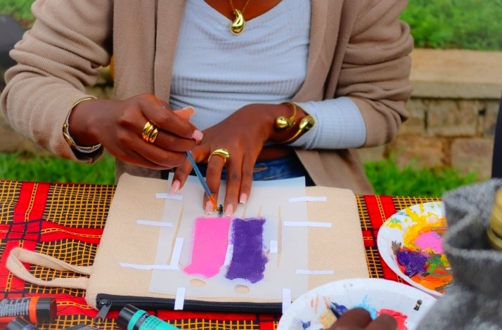 Person painting colorful designs on fabric using stencils and brushes.