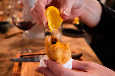 Hands squeezing a lemon wedge directly over a golden, savory empanada pastry pastry.